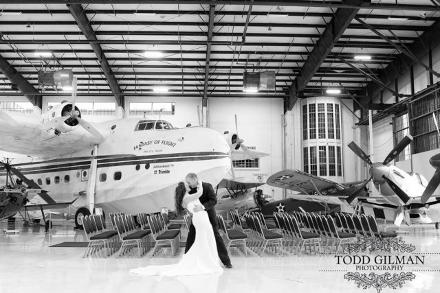 Bride and Groom embrace in front of Fantasy of Flight Short Sunderland